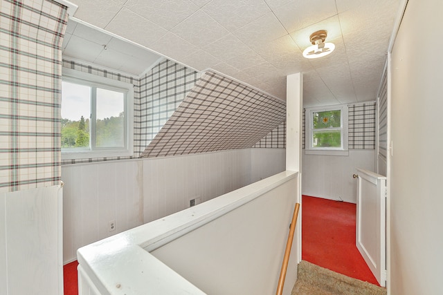 hall with carpet flooring and wooden walls