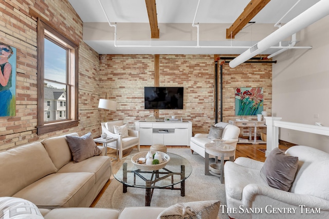 living room with beam ceiling, light hardwood / wood-style floors, and brick wall