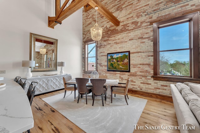 dining space with beamed ceiling, plenty of natural light, light wood-type flooring, and high vaulted ceiling