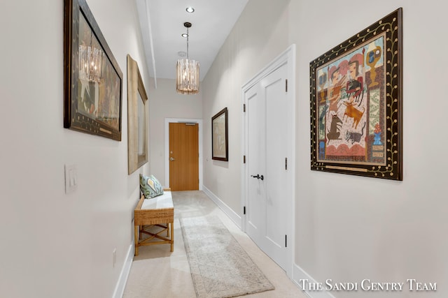 corridor featuring light colored carpet and a notable chandelier