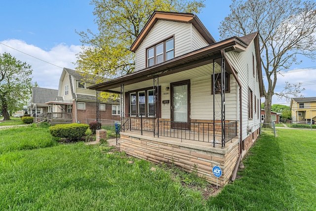 rear view of property featuring a yard and covered porch