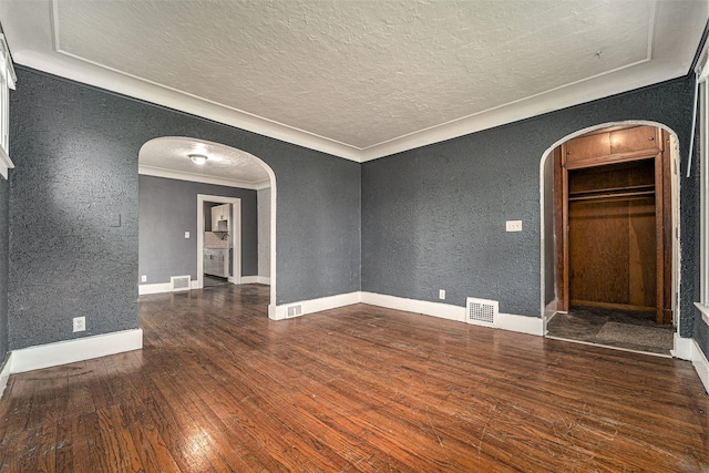 spare room with a textured ceiling, dark hardwood / wood-style floors, and crown molding