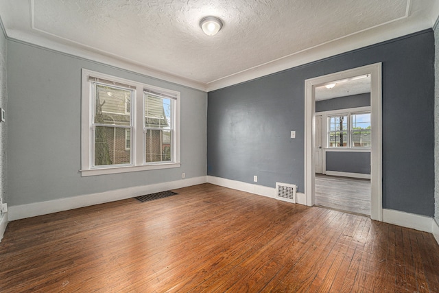 unfurnished room with crown molding, dark hardwood / wood-style flooring, and a textured ceiling