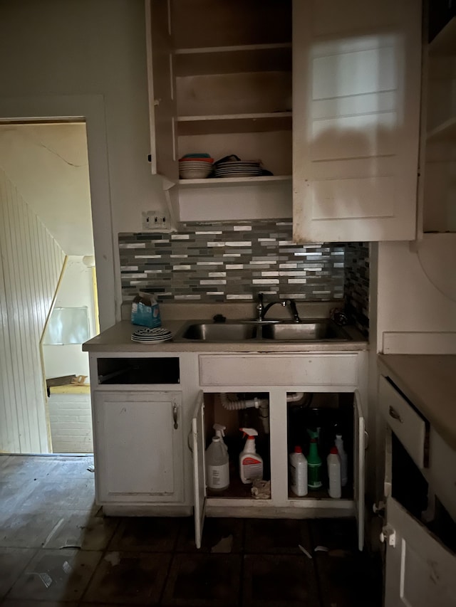 kitchen with white cabinets, backsplash, dark tile patterned flooring, and sink