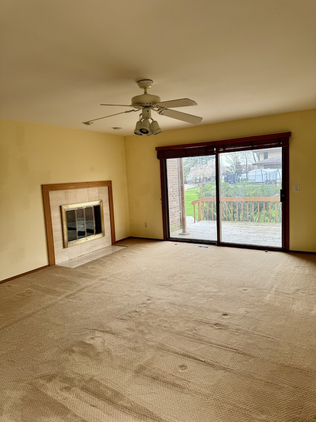 unfurnished living room featuring ceiling fan, a fireplace, and light colored carpet