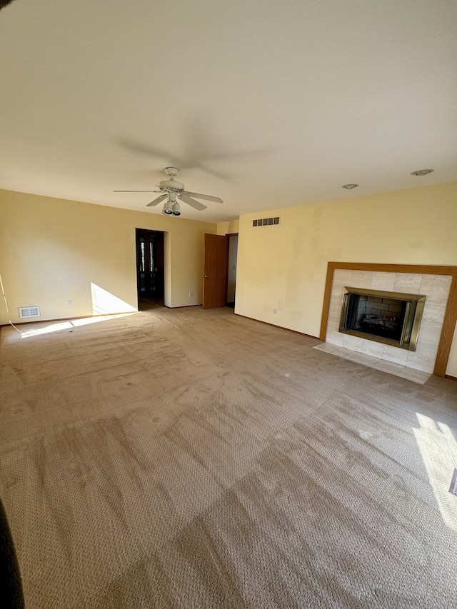 unfurnished living room with a fireplace, light colored carpet, and ceiling fan