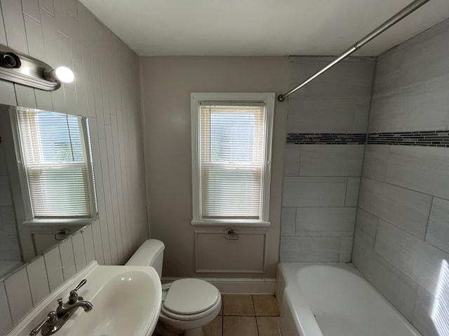 full bathroom with tile patterned floors, tiled shower / bath combo, toilet, and a wealth of natural light