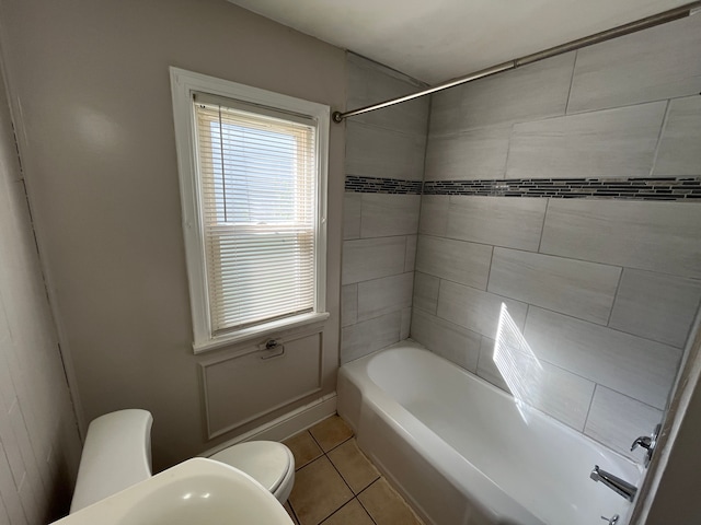 bathroom with tile patterned flooring, tiled shower / bath combo, and toilet