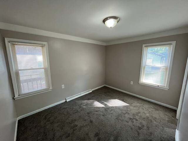 spare room featuring crown molding, a baseboard radiator, and dark colored carpet