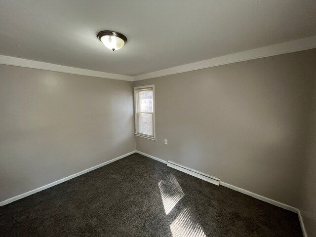 spare room featuring dark carpet, crown molding, and a baseboard heating unit