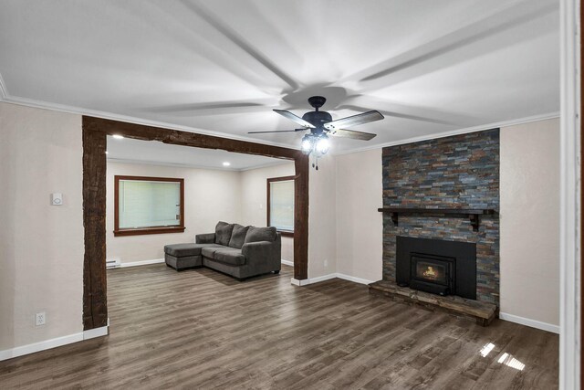 living room featuring ceiling fan, a stone fireplace, ornamental molding, and dark wood-type flooring