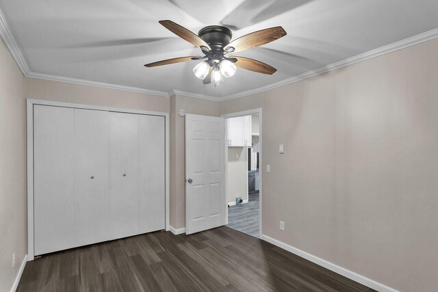 unfurnished bedroom featuring a closet, dark hardwood / wood-style floors, ceiling fan, and crown molding