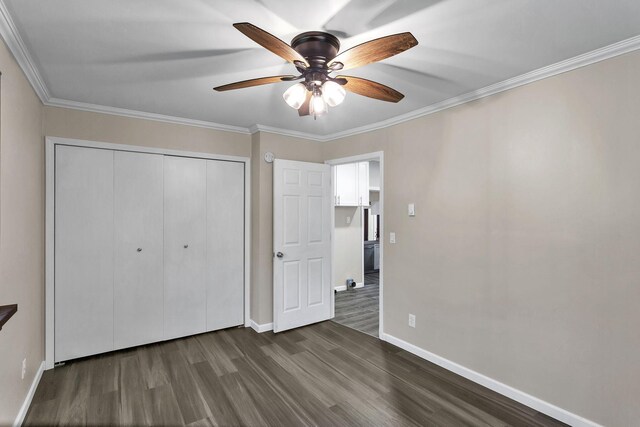 unfurnished bedroom featuring ceiling fan, dark hardwood / wood-style floors, ornamental molding, and a closet