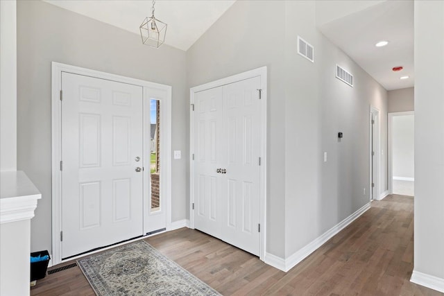 foyer featuring wood-type flooring and vaulted ceiling