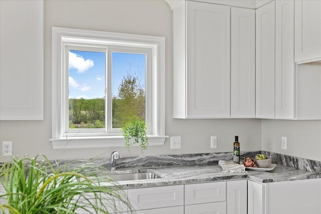 kitchen with sink, white cabinets, and light stone counters