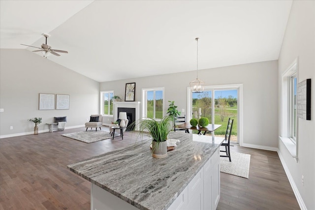 kitchen featuring decorative light fixtures, white cabinetry, dark hardwood / wood-style flooring, light stone counters, and a healthy amount of sunlight