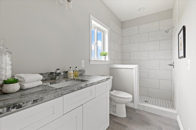 bathroom with vanity, toilet, and a tile shower