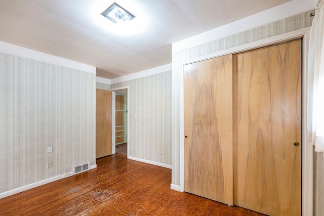 unfurnished bedroom with a closet and dark wood-type flooring