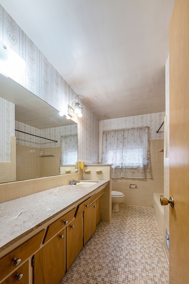 full bathroom featuring vanity, toilet, tile walls, and tiled shower / bath combo