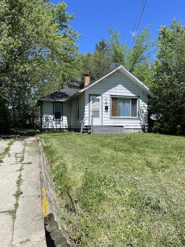 2734 Cumings Ave, Flint, MI 48503 - bungalow featuring a chimney, a front yard, entry steps, and driveway