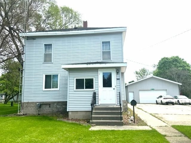 view of front of home featuring a front yard, a garage, and an outdoor structure