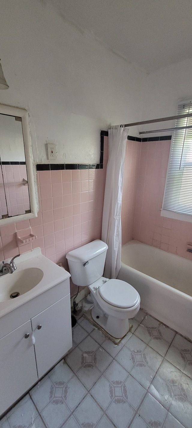 full bathroom with shower / tub combo, tile patterned floors, toilet, vanity, and tile walls