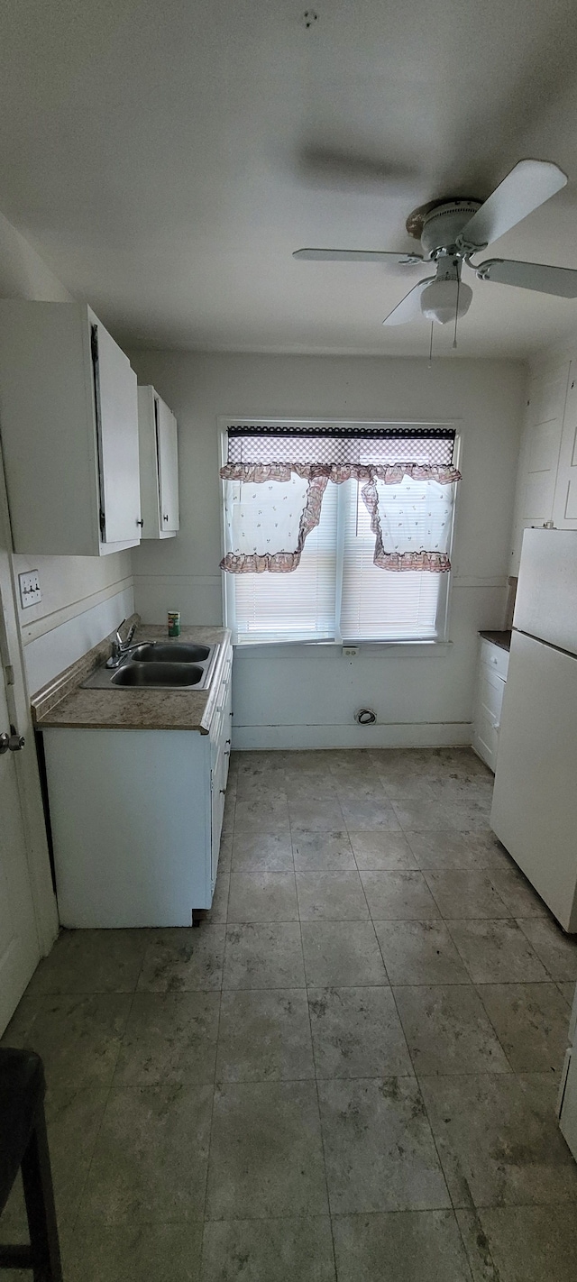 kitchen with white cabinets, white fridge, ceiling fan, and sink