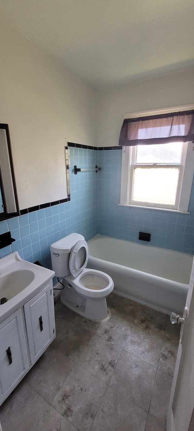 full bathroom featuring vanity, tile patterned floors, tiled shower / bath combo, toilet, and tile walls