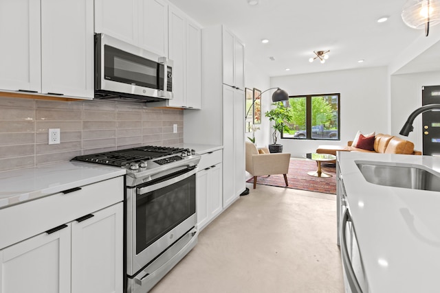 kitchen with white cabinets, sink, light stone countertops, tasteful backsplash, and stainless steel appliances