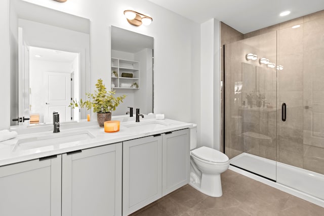 bathroom featuring tile patterned floors, vanity, a shower with shower door, and toilet