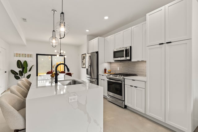 kitchen with sink, white cabinets, stainless steel appliances, and decorative light fixtures