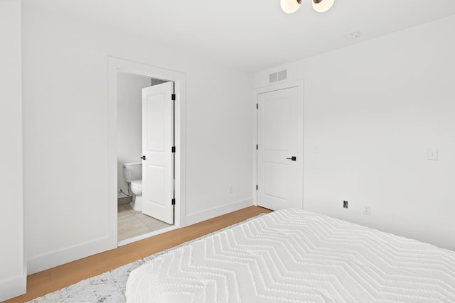 bedroom featuring connected bathroom and light hardwood / wood-style floors