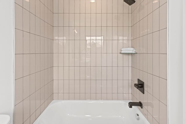 bathroom featuring toilet and tiled shower / bath