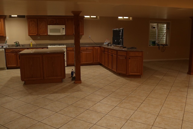 kitchen with kitchen peninsula, white appliances, sink, a kitchen island, and light tile patterned flooring