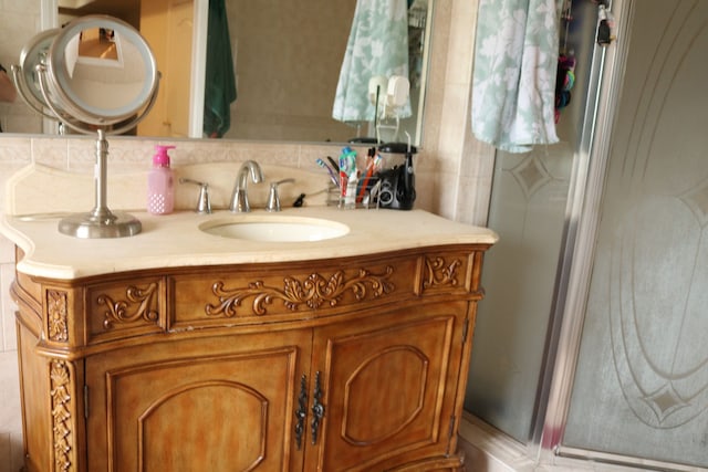 bathroom with decorative backsplash, vanity, and a shower with shower door