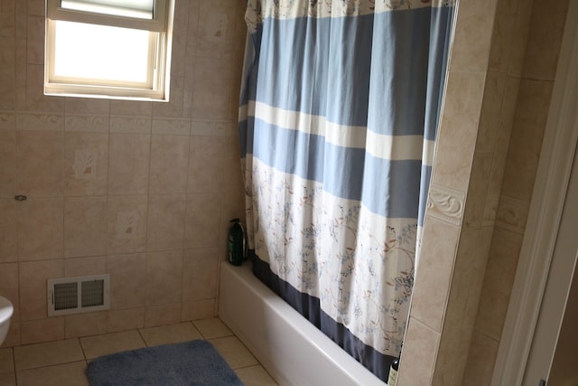 bathroom featuring tile patterned flooring, shower / bath combination with curtain, toilet, and tile walls