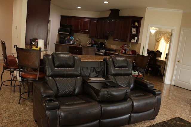 kitchen with sink, crown molding, decorative backsplash, dark brown cabinetry, and a breakfast bar area