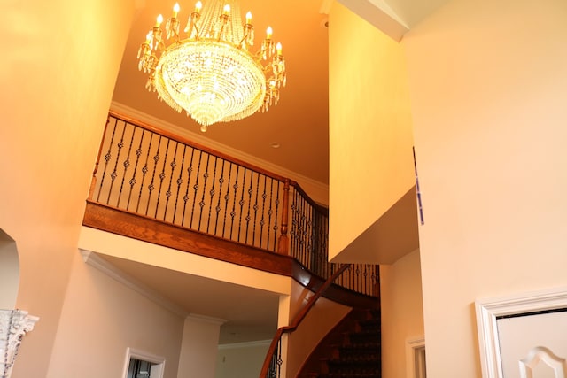 staircase with crown molding, a high ceiling, and a chandelier