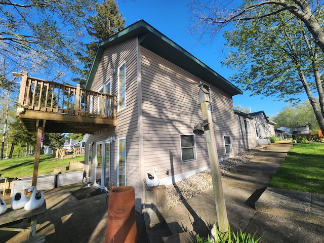 view of side of property with a deck, a patio area, and a lawn