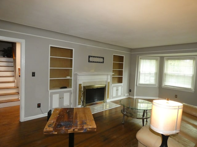 unfurnished living room with dark hardwood / wood-style floors and built in shelves