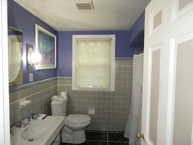 bathroom featuring a shower with curtain, sink, tile walls, tile patterned flooring, and toilet