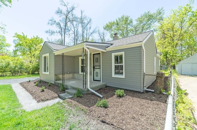 view of front of house with fence, driveway, roof with shingles, a porch, and a chimney