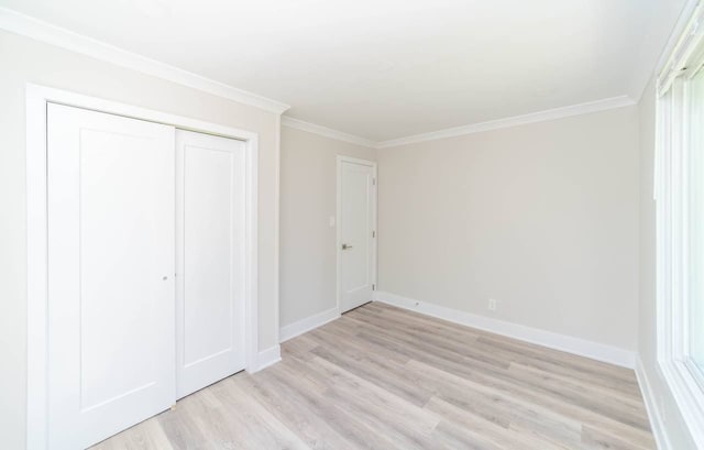 unfurnished bedroom featuring light wood finished floors, a closet, crown molding, and baseboards