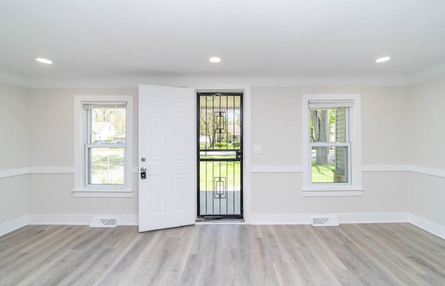 entryway featuring plenty of natural light, light wood-type flooring, and ornamental molding