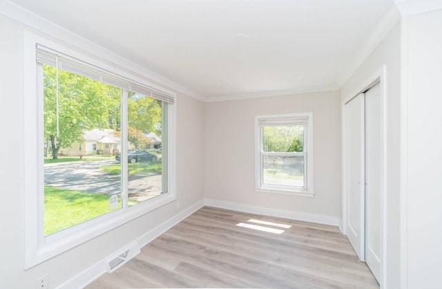 unfurnished room featuring visible vents, light wood-type flooring, baseboards, and ornamental molding