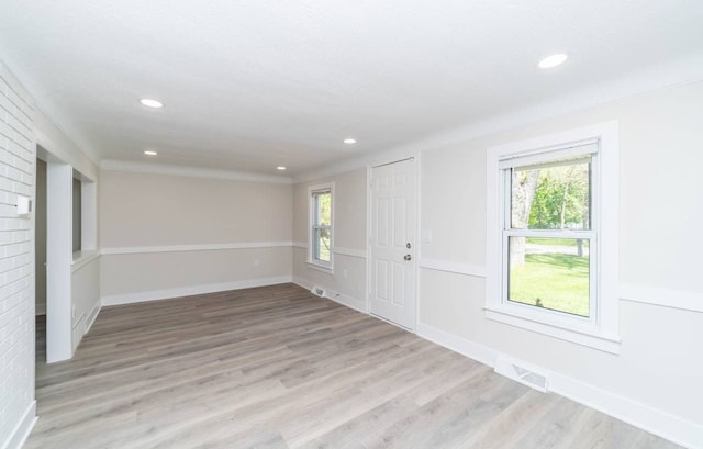 empty room with a fireplace, light hardwood / wood-style flooring, and a healthy amount of sunlight