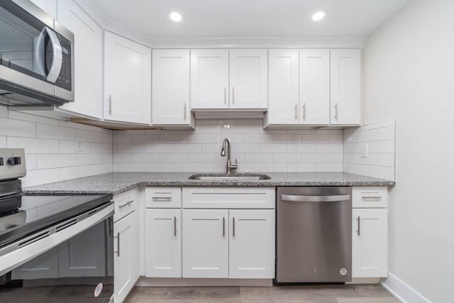 kitchen featuring a sink, light stone counters, appliances with stainless steel finishes, and white cabinetry