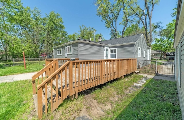 back of property with a lawn, a gate, fence, a wooden deck, and a chimney