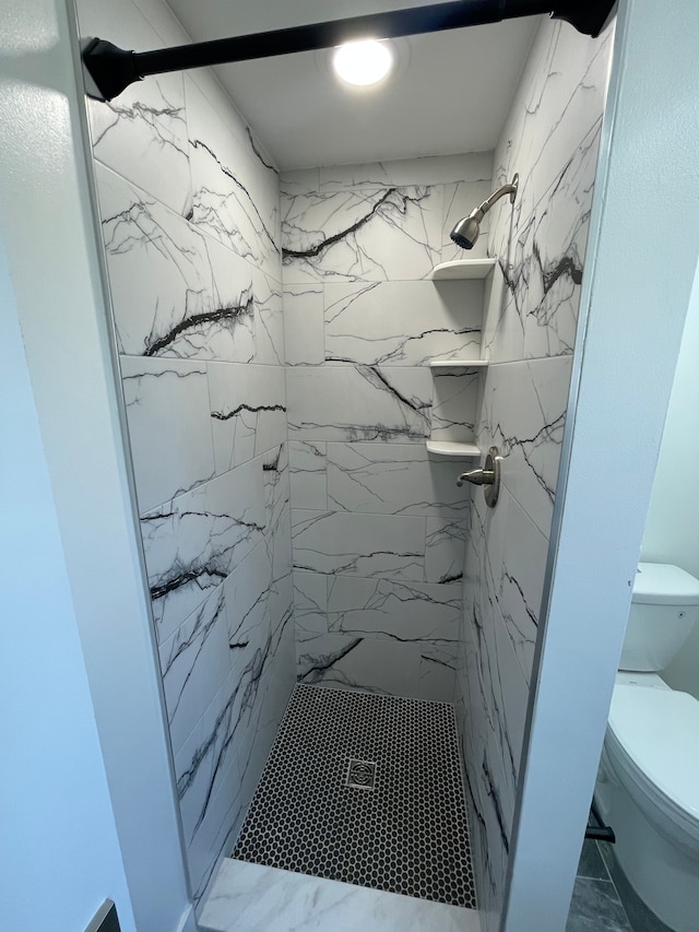 bathroom featuring a marble finish shower, marble finish floor, and toilet