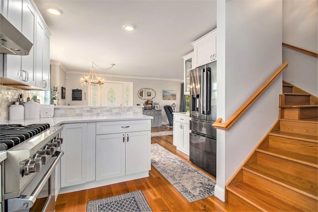 kitchen featuring backsplash, white cabinets, range hood, and high end appliances